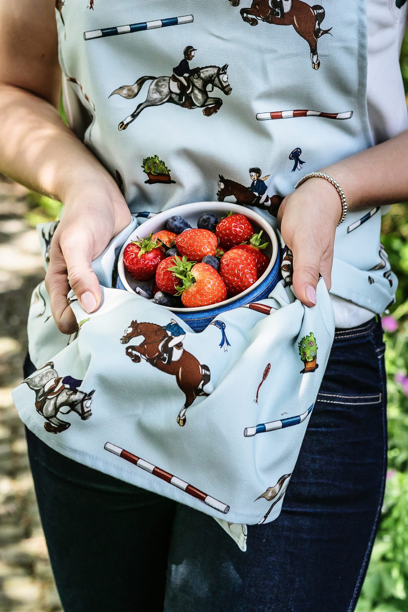 Showjumping patterned apron underneath a bowl of strawberries