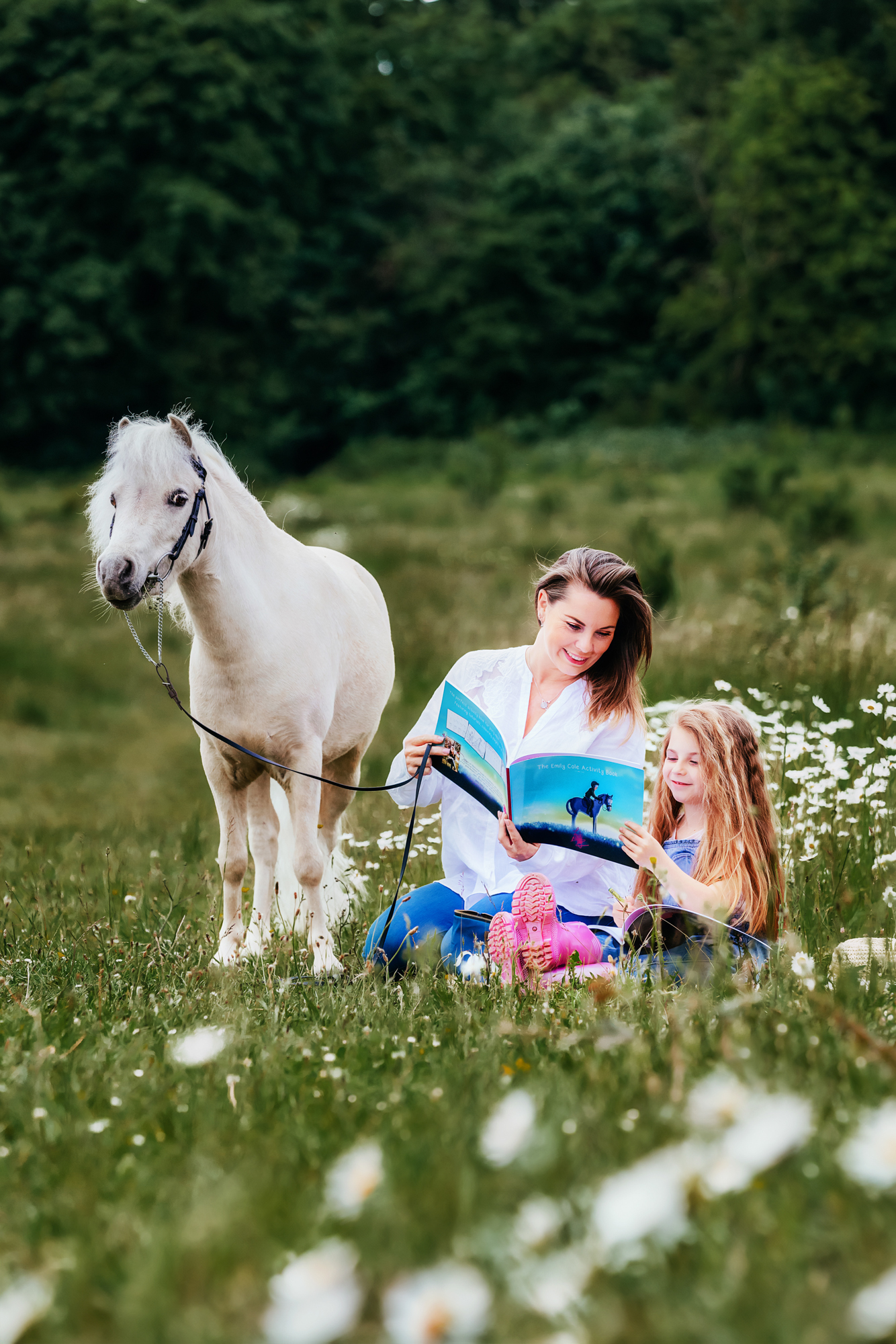 Mum and daughter sat with a pony looking at the The Emily Cole activity books for adults and children
